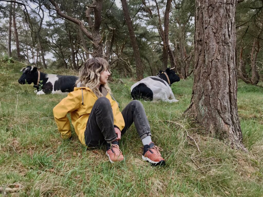 Foto bij blog over merkverhaal. Schrijfwijze Peggy poseert bij koeien. 